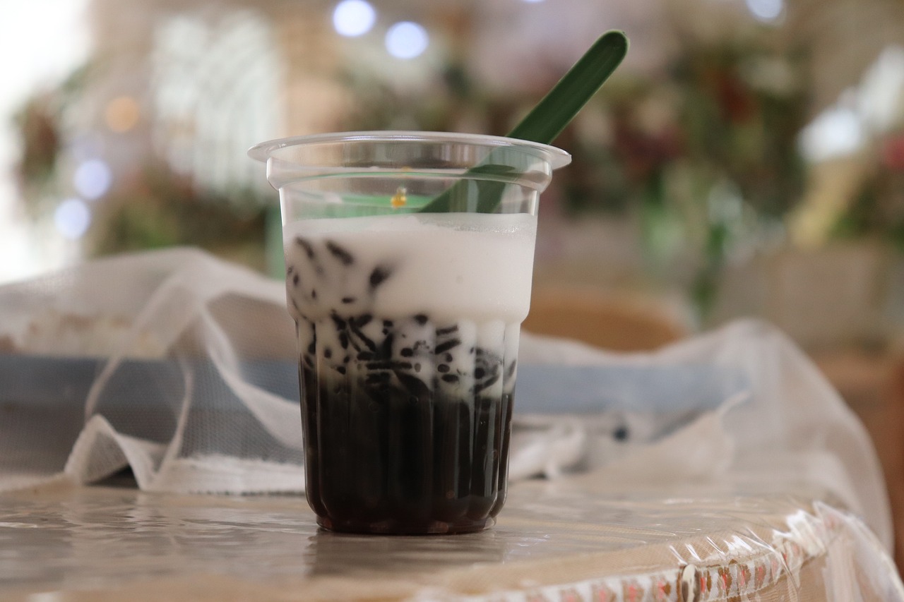 Cendol yang disajikan dengan gula merah dan santan dalam gelas plastik di atas meja