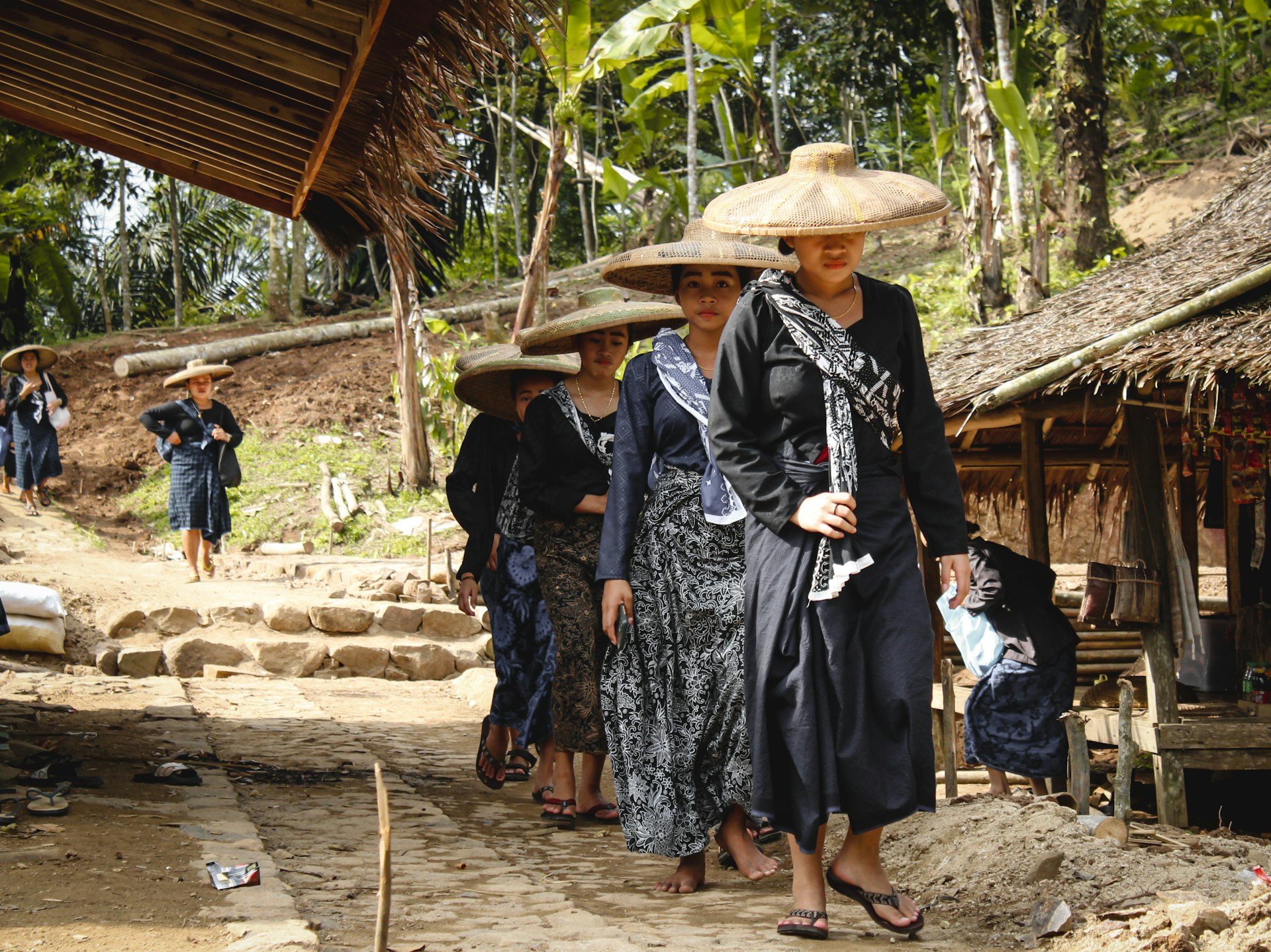 Wanita Baduy Luar yang sedang berjalan, mengenakan pakaian berwarna hitam