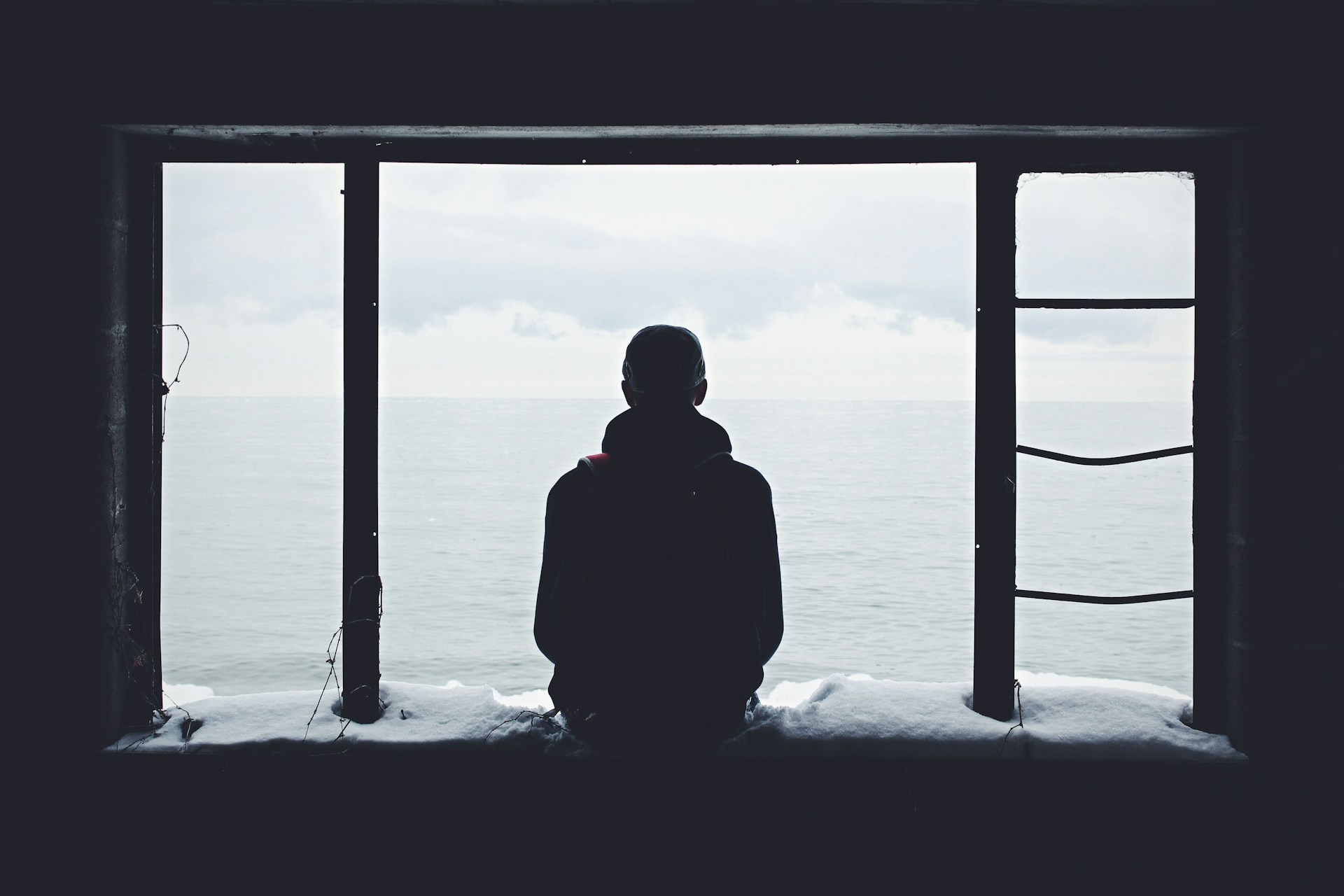 Seseorang yang berdiri menghadap jendela dalam kesendirian | Silhouette of a man (image: Noah Silliman, Unsplach)