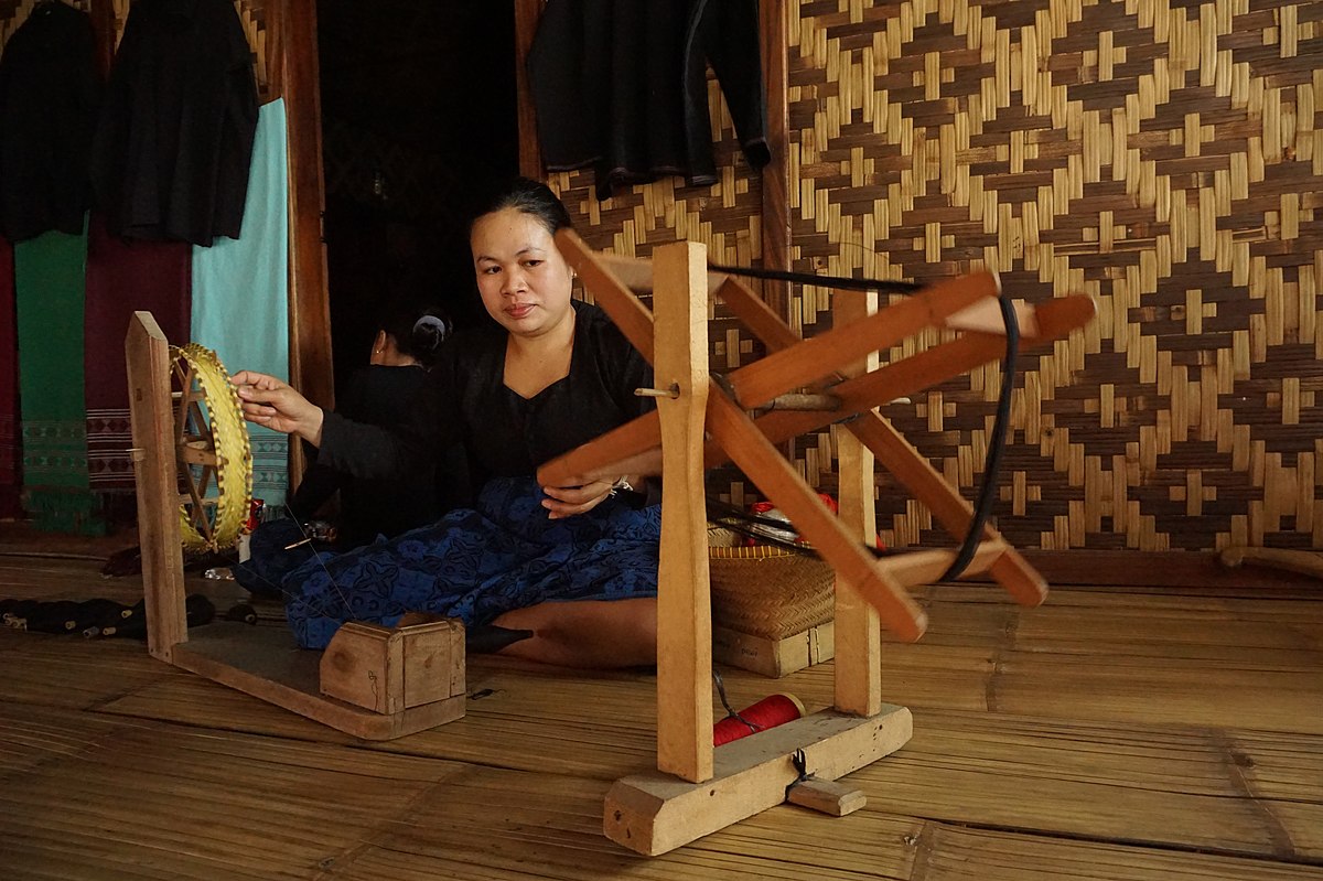 Seorang wanita dari Suku Badut sedang memintal benang dengan alat tradisioanal