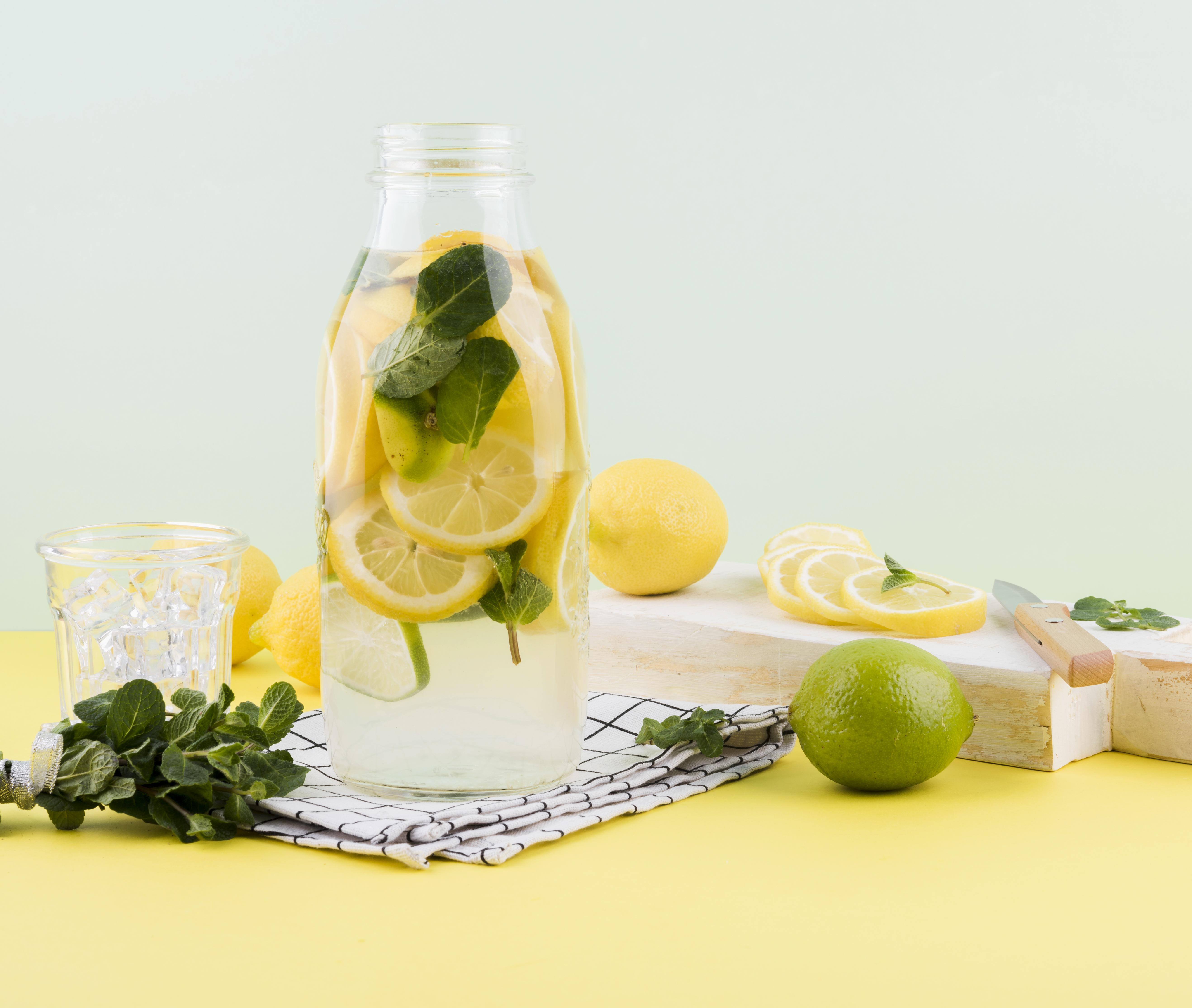 Ilustrasi beberapa lemon dan potongannya, serta lemon yang berada dalam botol kaca