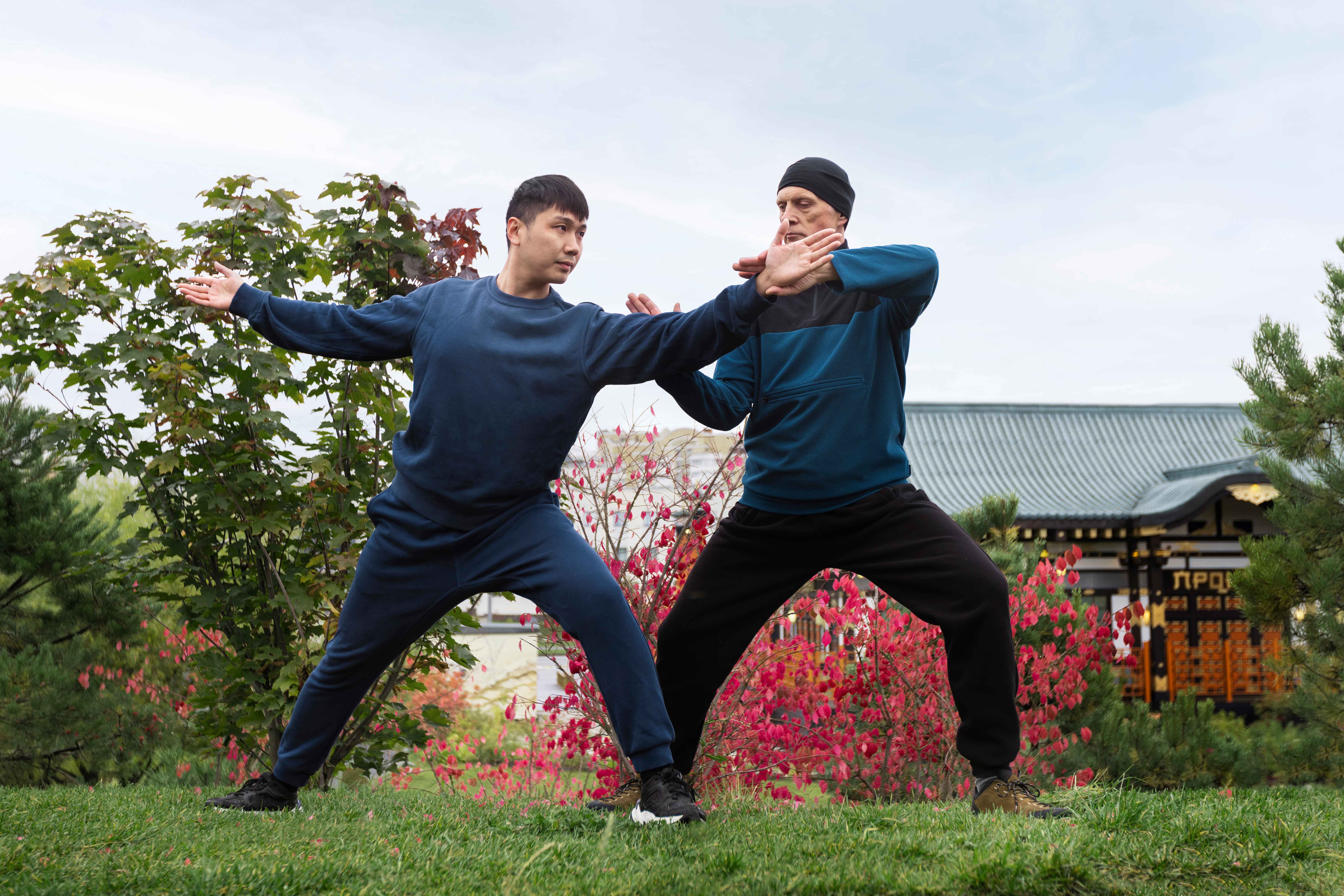 Dua orang lelaki, lelaki pertama melakukan gerakan tai chi dan lelaki kedua mengarakan gerakan tai chi yang tepat