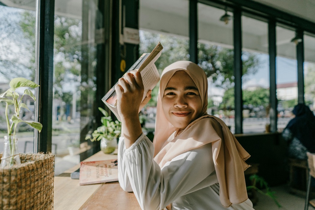 https://www.pexels.com/photo/smiling-hijab-girl-enjoying-a-book-in-a-cozy-coffee-shop-in-the-city-15938260/