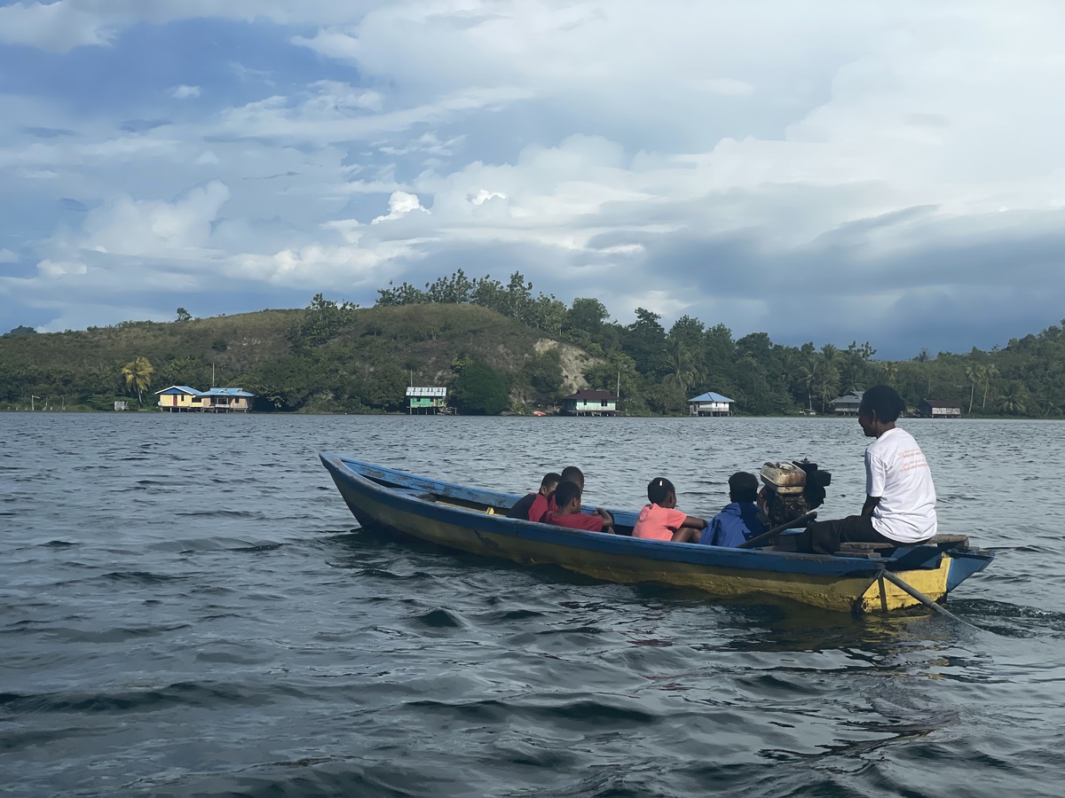 Mama Yunne menjemput anak-anak naik perahu ke Rumah Baca