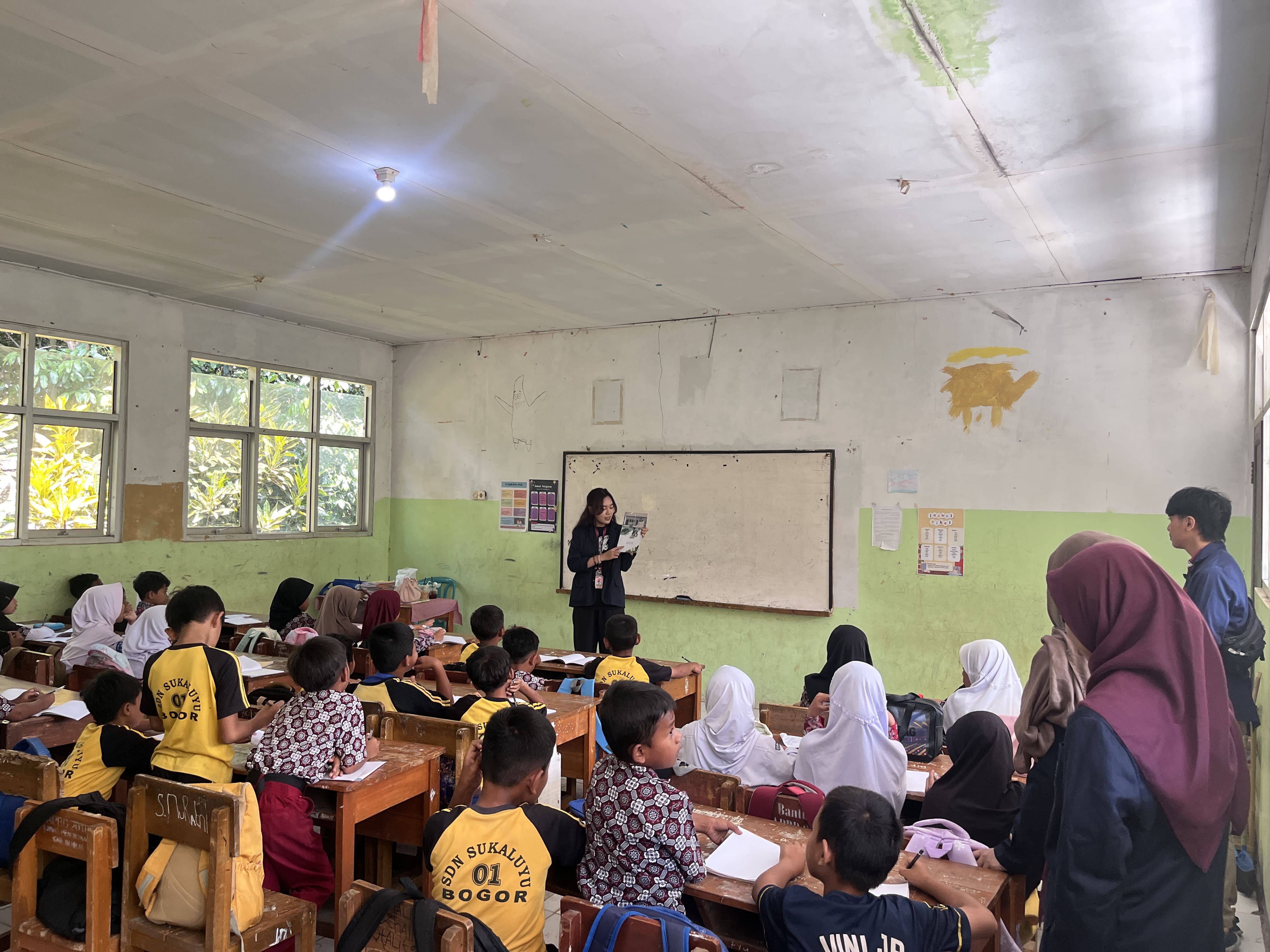 Jennyta Putri Lestari, Mahasiswa KKN‑T Literasi IPB, membacakan cerita kepada siswa SDN 01 Sukaluyu dalam sesi Read Me a Book © Dokumentasi Pribadi/Tim BOGORKAB12