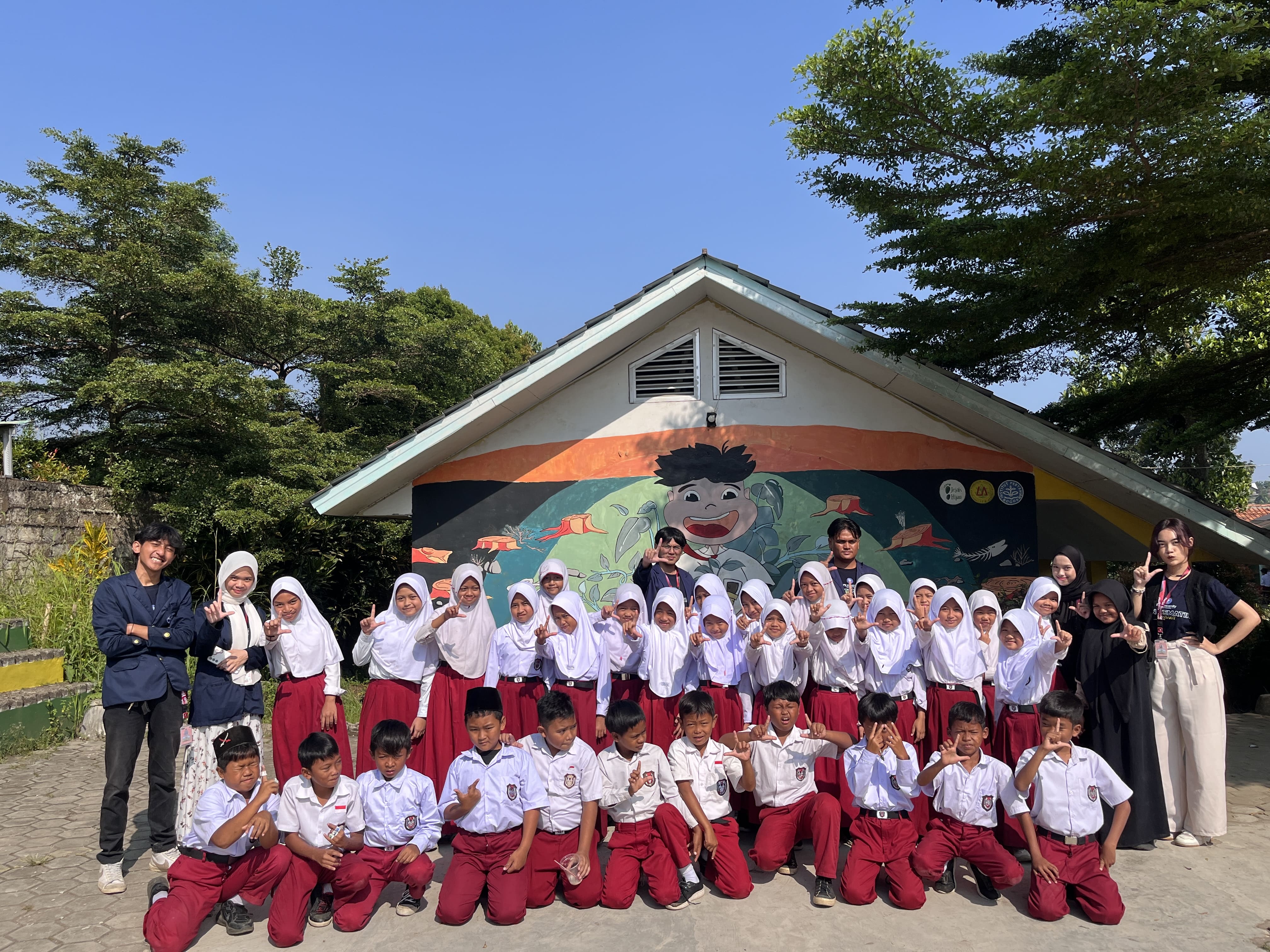 Anak-anak SDN 01 Sukaluyu bersama tim KKN-T Literasi IPB berpose di depan mural “Aku & Buku” © Dokumentasi Pribadi/Tim BOGORKAB12