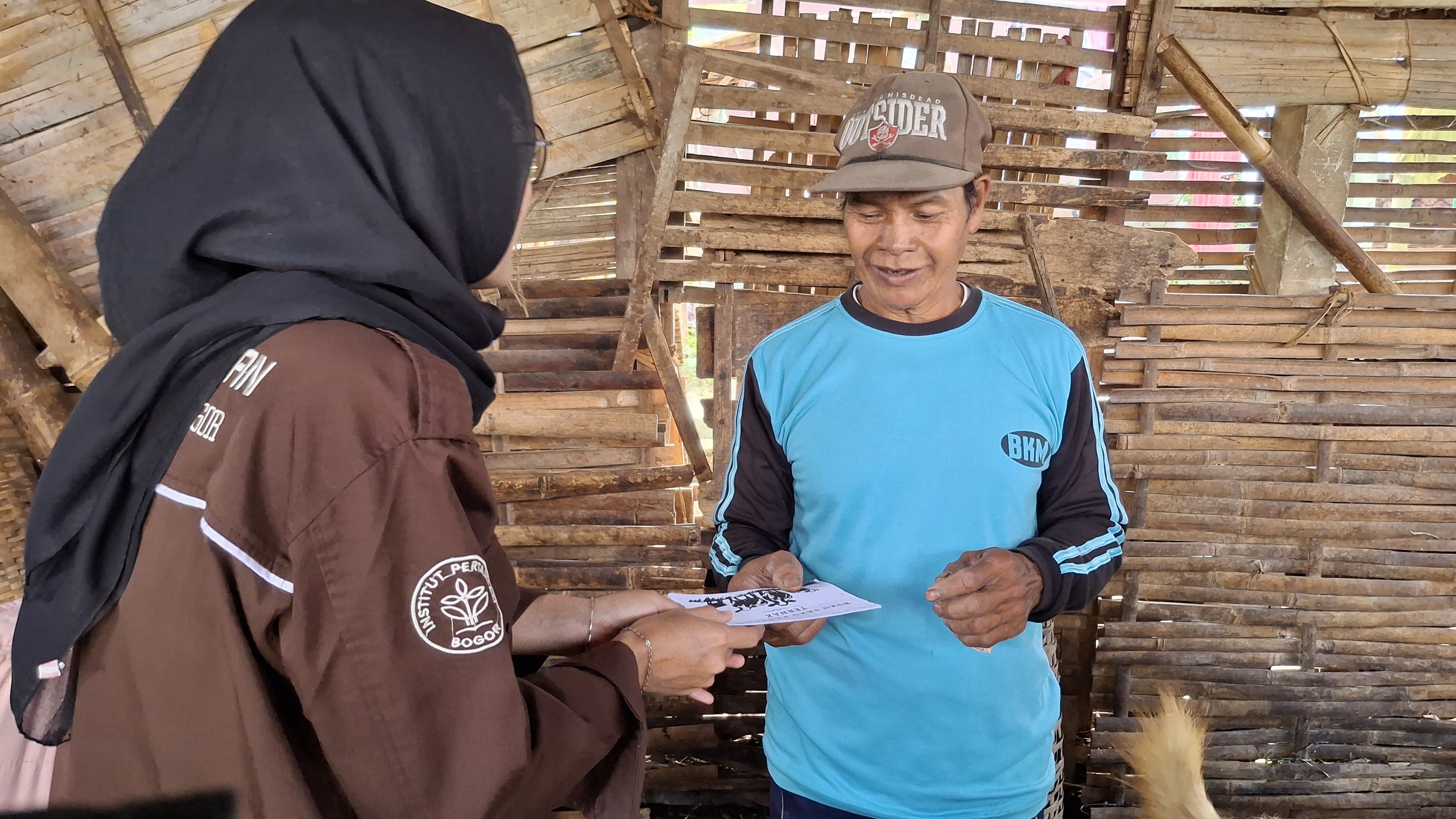 Mahasiswa KKN IPB University memberikan buku saku penyakit ternak kepada peternak di Desa Paweden sebagai media edukasi kesehatan hewan.