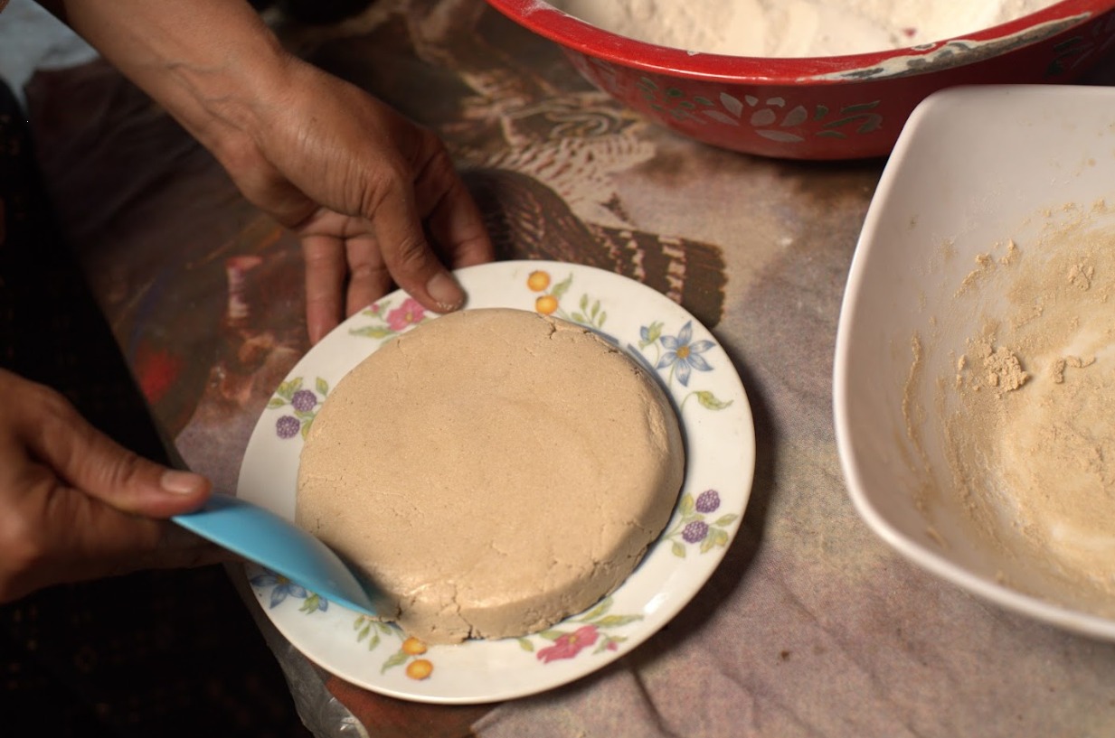 Membentuk Bareh Randang di sebuah piring setelah proses pencampuran tepung beras ketan dengan gula yang sudah dicairkan. Foto oleh Rekam Indonesia/GNFI