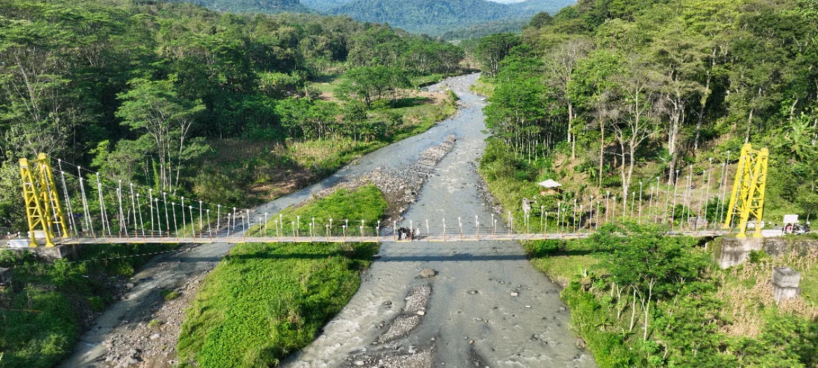 Pemandangan alam pedesaan Desa Muncar di Temanggung, dengan hamparan persawahan hijau yang luas dan pemandangan asri di jembatan