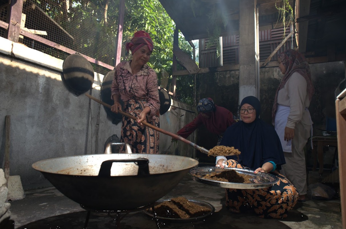 Rendang Paku yang sudah matang diangkat dari kuali besar, dipindahkan ke nampan untuk didinginkan sebelum siap dikemas. Foto oleh Rekam Indonesia/GNFI