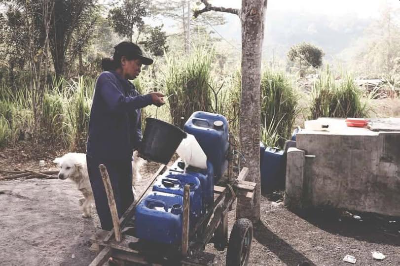 Potret seorang ibu yang sedang mengisi air ke dalam jirigen sebelum ia dorong menuju rumahnya | Dokumentasi foto oleh Reza