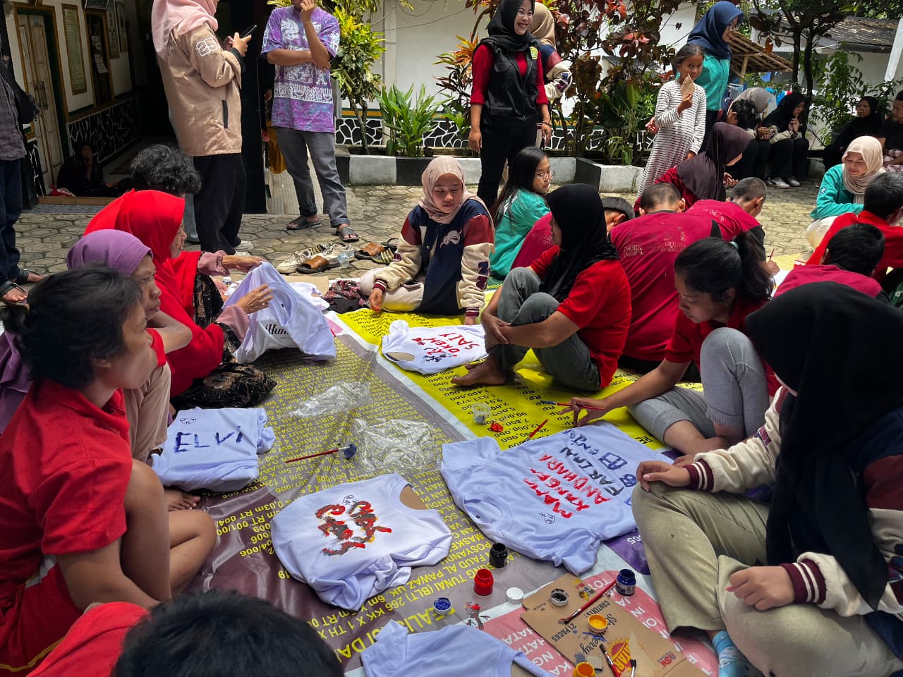 Peserta kegiatan Sahabat Jiwa melukis emosi di atas kaos putih bertuliskan “Sahabat Jiwa BEM FEMA X HUMANIES PROJECT” dengan bimbingan fasilitator, mengekspresikan perasaan melalui warna dan goresan kuas.