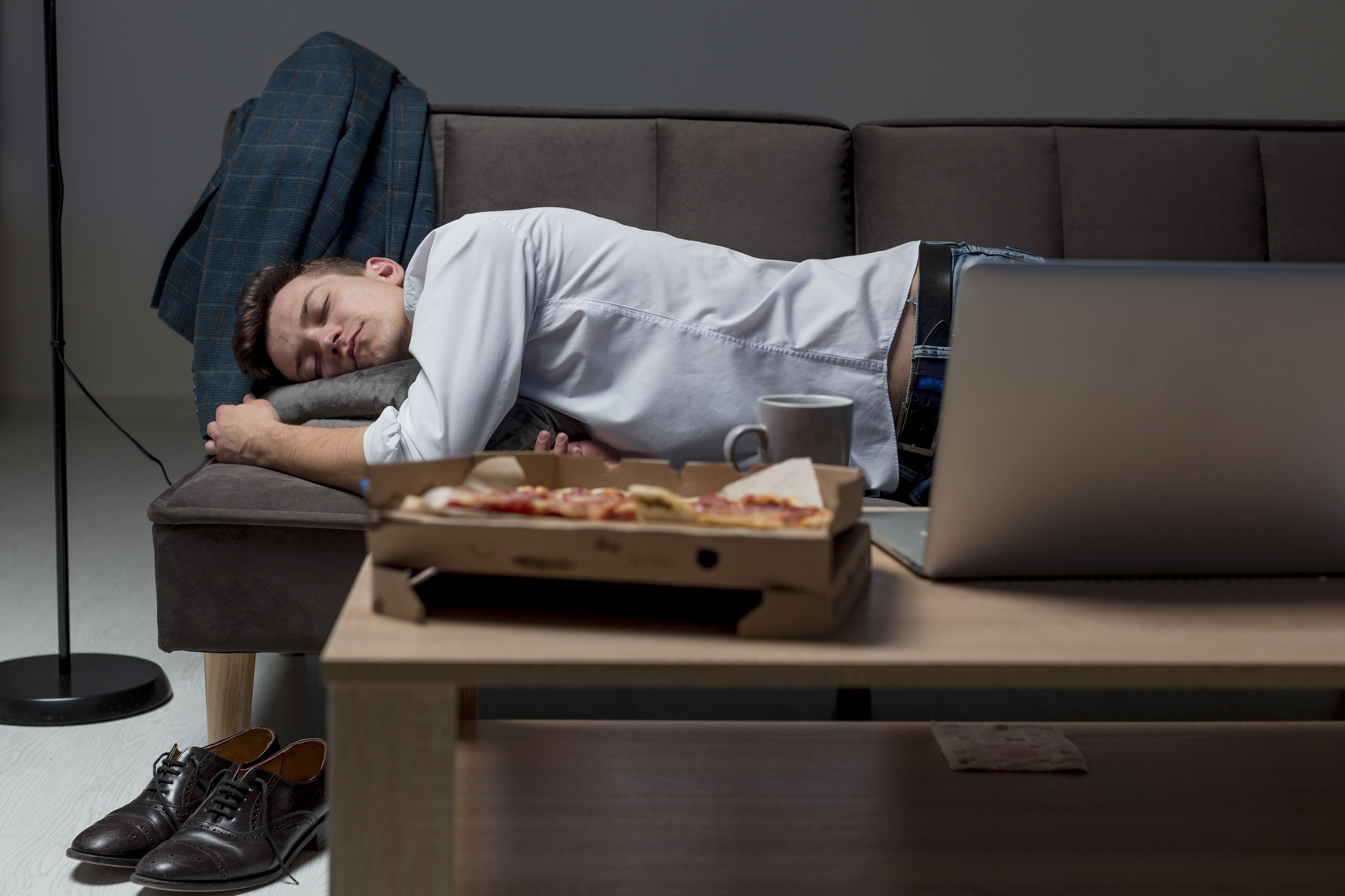 Dewasa muda yang tertidur lelah setelah makan makanan junk food