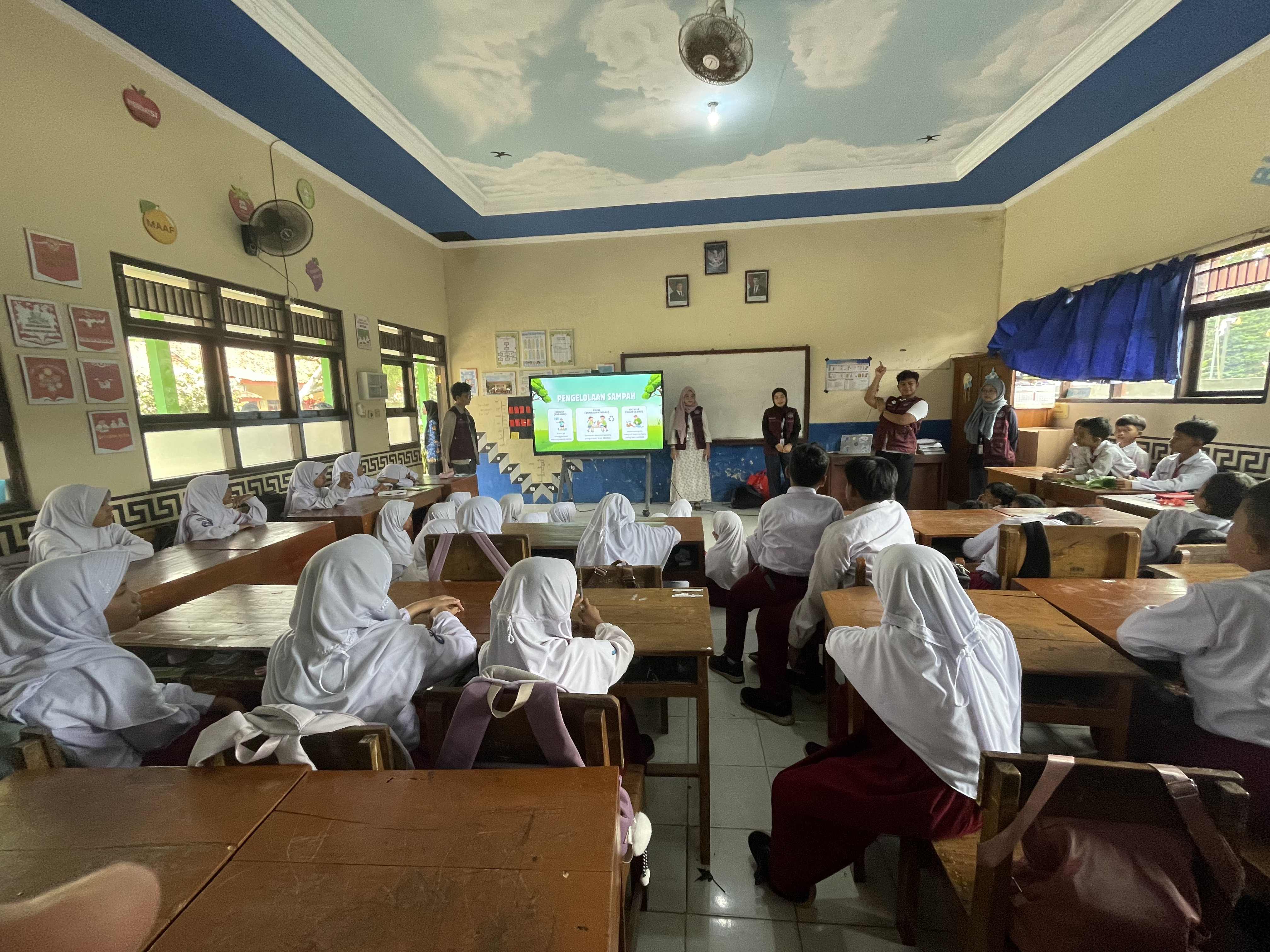 Foto mahasiswa KKNT sedang menjelaskan materi Hari Anak Nasional dan teknik ecoprint di depan kelas