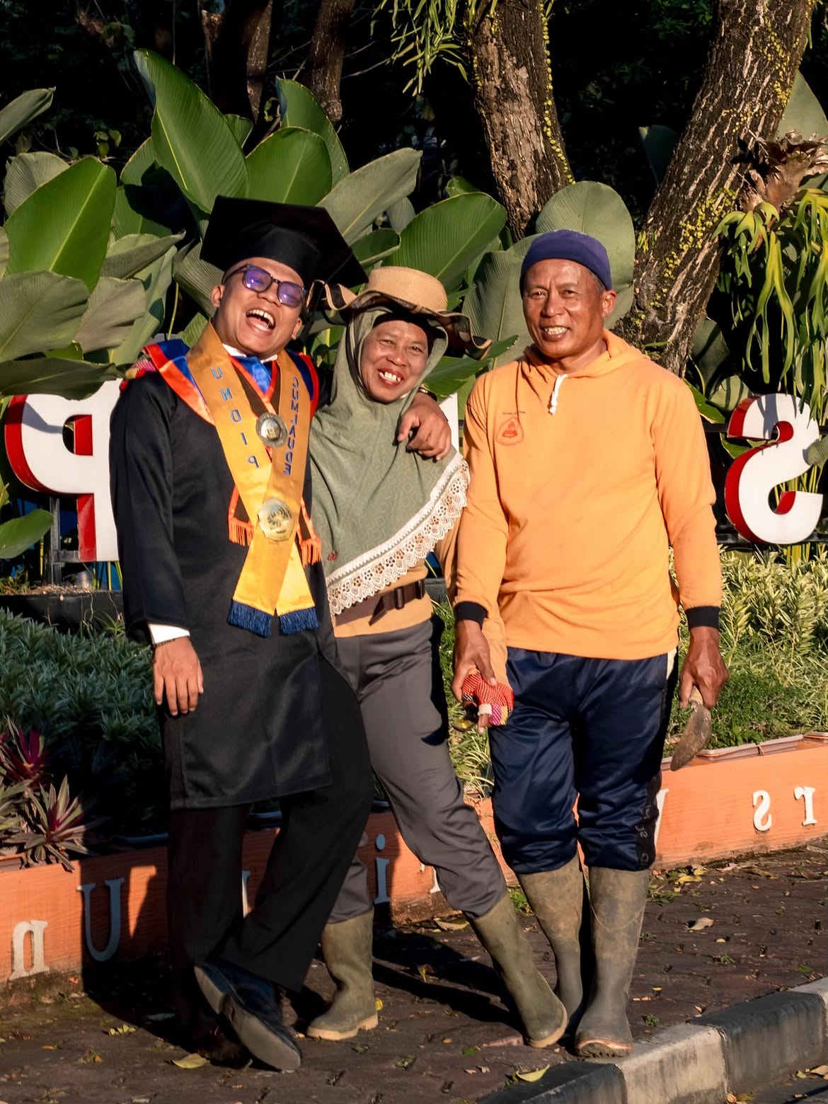 Kristiyawanto berfoto bersama kedua orang tuanya usai Wisuda ke-183 Universitas Diponegoro, dengan latar taman FISIP Undip