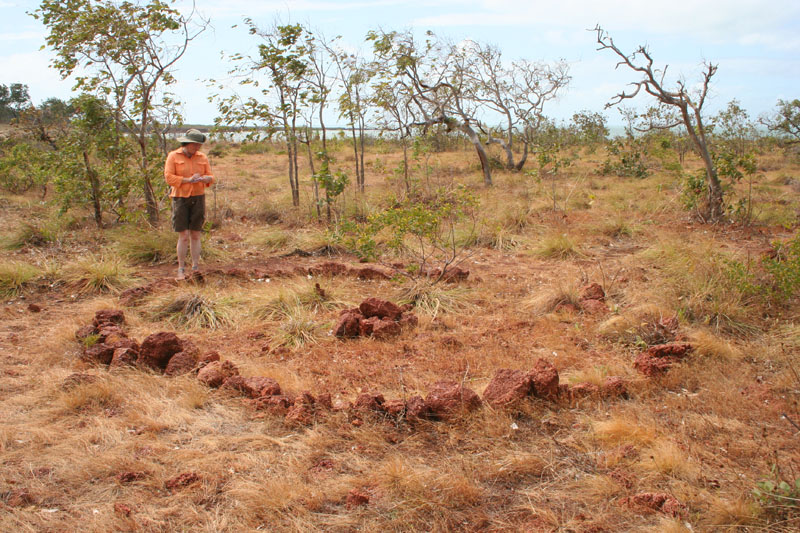 Seorang peneliti memeriksa susunan batu peninggalan era perdagangan teripang di pesisir Arnhem Land, Australia. Situs semacam ini, yang tersebar di sepanjang pantai Arnhem Land dan Kimberley, diyakini sebagai sisa tungku perapian atau denah kamp pengolahan teripang yang dulu digunakan pelaut Makassar dan Bugis. Foto: Ray Norris/Wikimedia Commons (CC BY-SA 2.5).