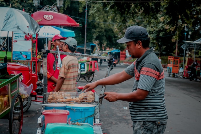 Pedagang Menggoreng Lumpia (https://unsplash.com/photos/a-man-is-cooking-food-on-a-cart-i3R1qn9JLaE)