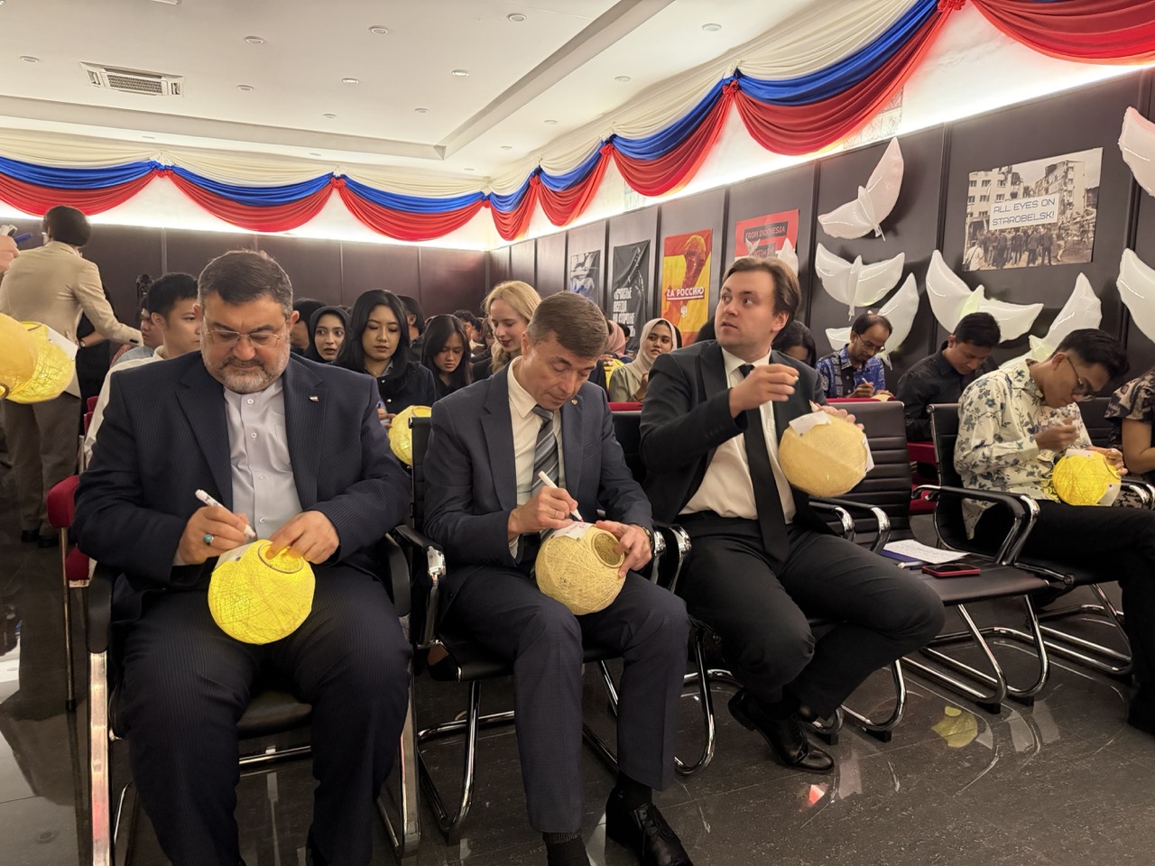 The Ambassadors of Iran and Russia, together with the Head of the Russian House, decorate paper lanterns with handwritten messages of peace and hope for children affected by conflict