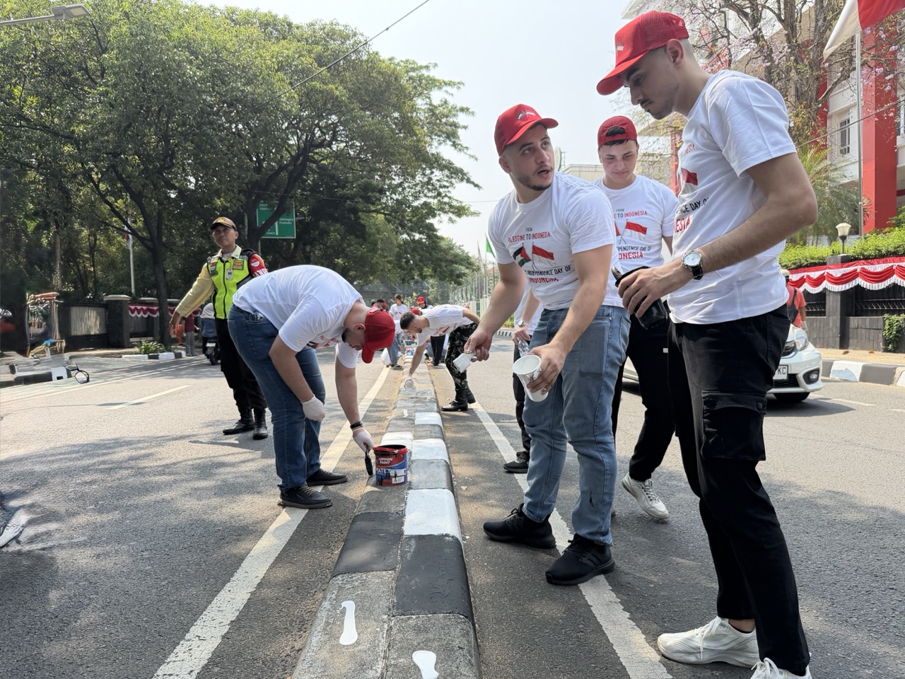 Palestinian students paint roadside barriers alongside local residents, turning educational ties into community participation and cultural exchange.