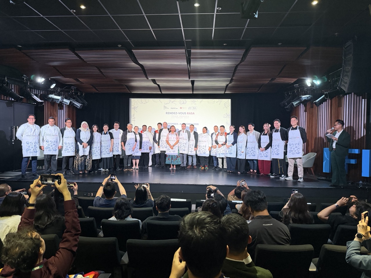 Speakers and participating partners receive festival aprons, symbolizing collaboration at the opening of Rendez-Vous Rasa 2026 in Jakarta.