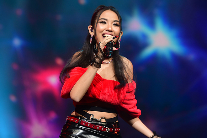 Thai rapper MILLI performing live on stage in a red outfit with vibrant lighting