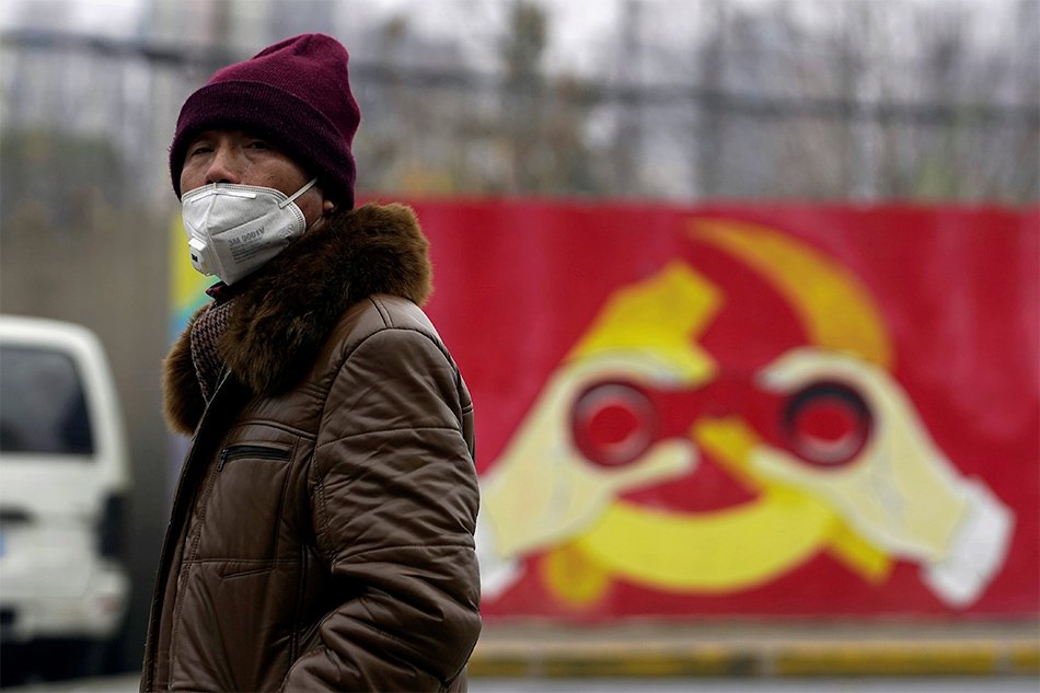 A man wears a mask as he walks past a mural showing a modified image of the Chinese Communist Party emblem in Shanghai, China after the country is hit by an outbreak of the new coronavirus, January 28, 2020. Image: Aly Song, Reuters