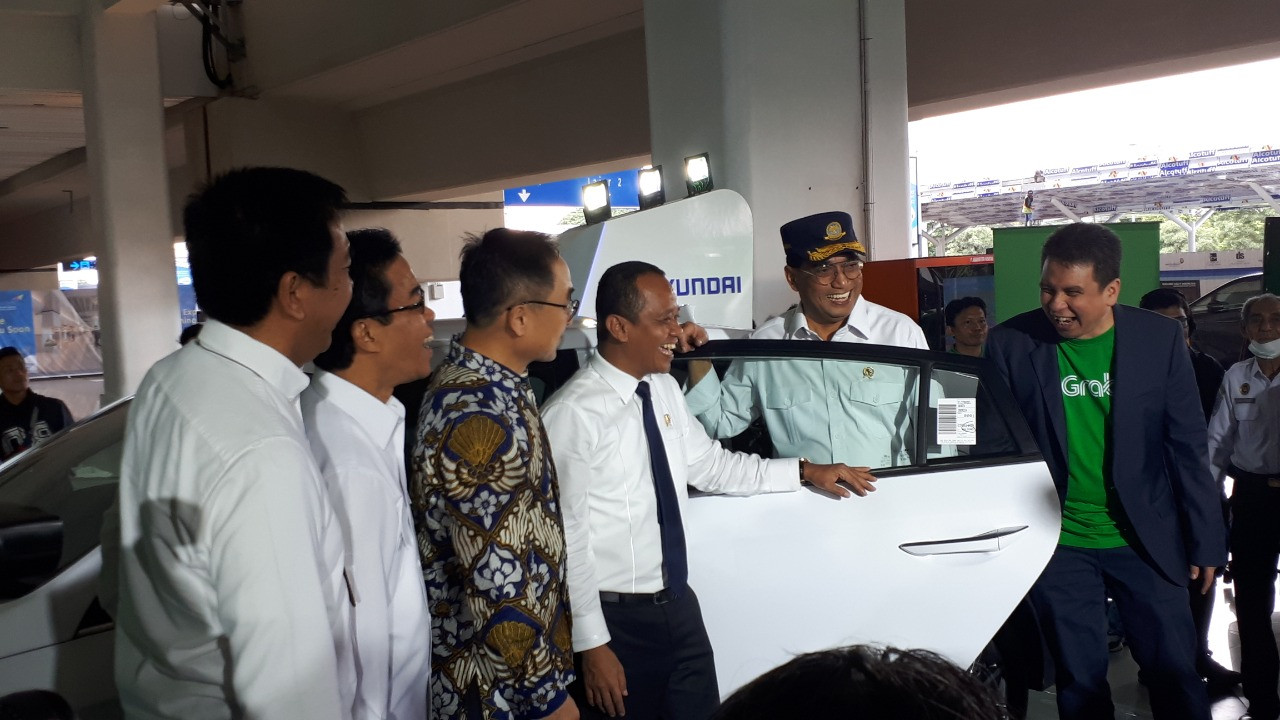 Grab Indonesia president director Ridzki Kramadibrata (right) shares a laugh with Transportation Minister Budi Karya Sumadi (second right) as the latter emerges from a Hyundai Ioniq Electric car at Soekarno-Hatta International Airport on Jan. 27, 2019. The minister was trying out the electric vehicle during the launch of the new GrabCar Elektrik e-taxi service on Monday. Image: JP/Eisya Eloksari